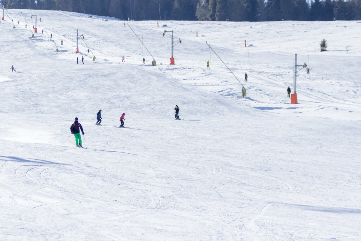 Slope with drag lifts and skiers on a sunny day